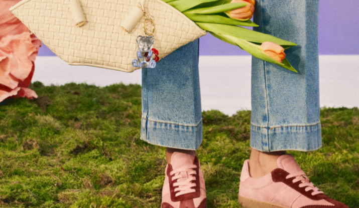Person in jeans with pink shoes holding tulips and woven bag