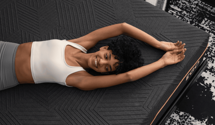 Happy woman stretching on textured black mattress