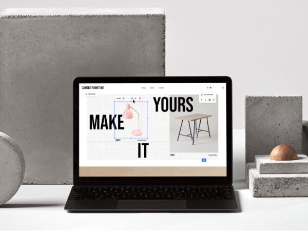 Laptop displaying furniture design site surrounded by concrete blocks