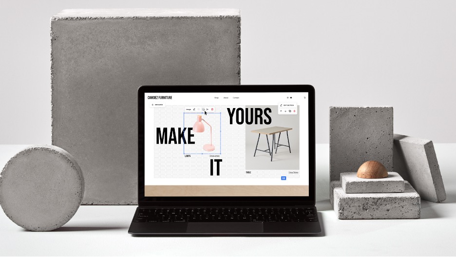 Laptop displaying furniture design site surrounded by concrete blocks