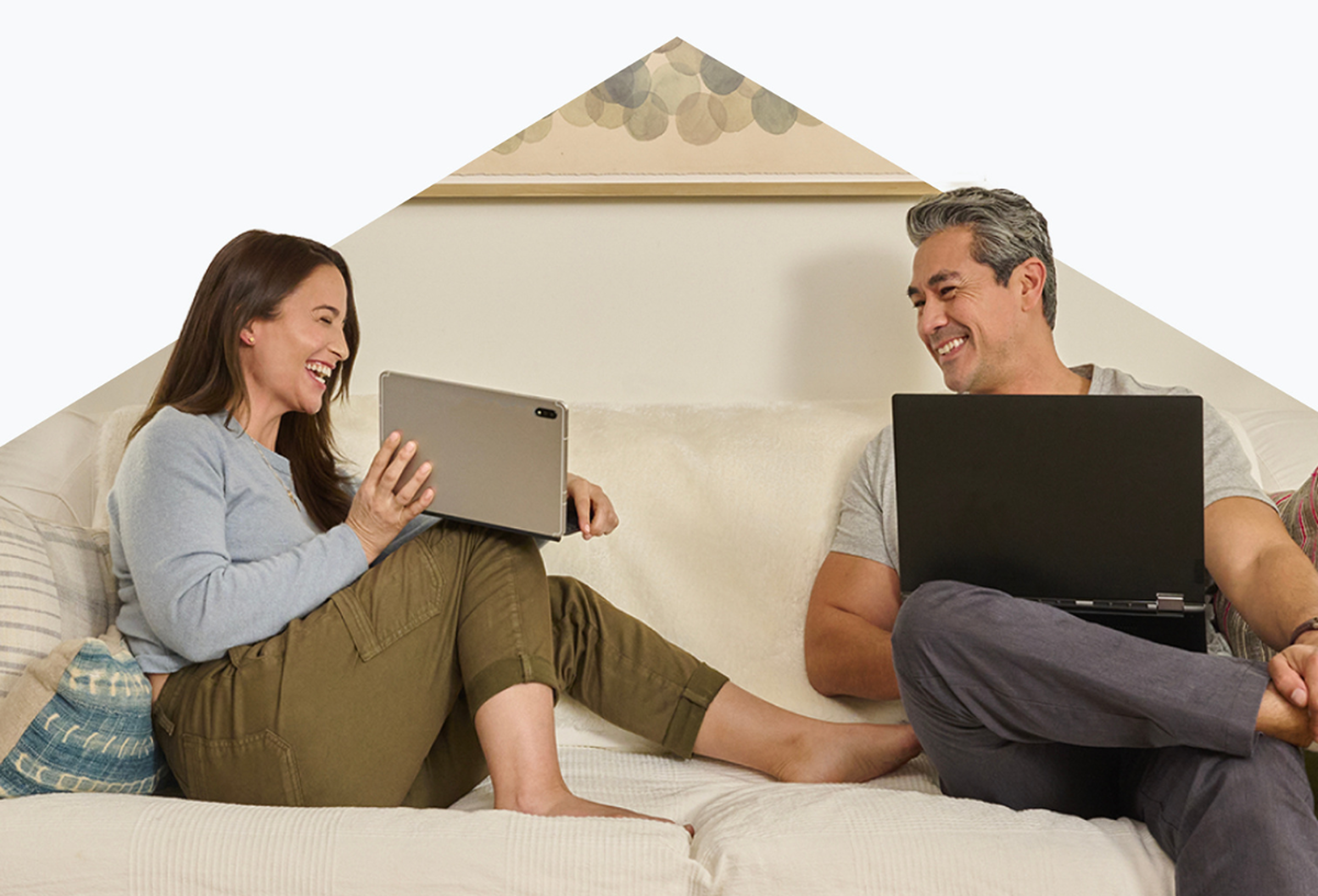 Smiling couple using tablet and laptop on sofa