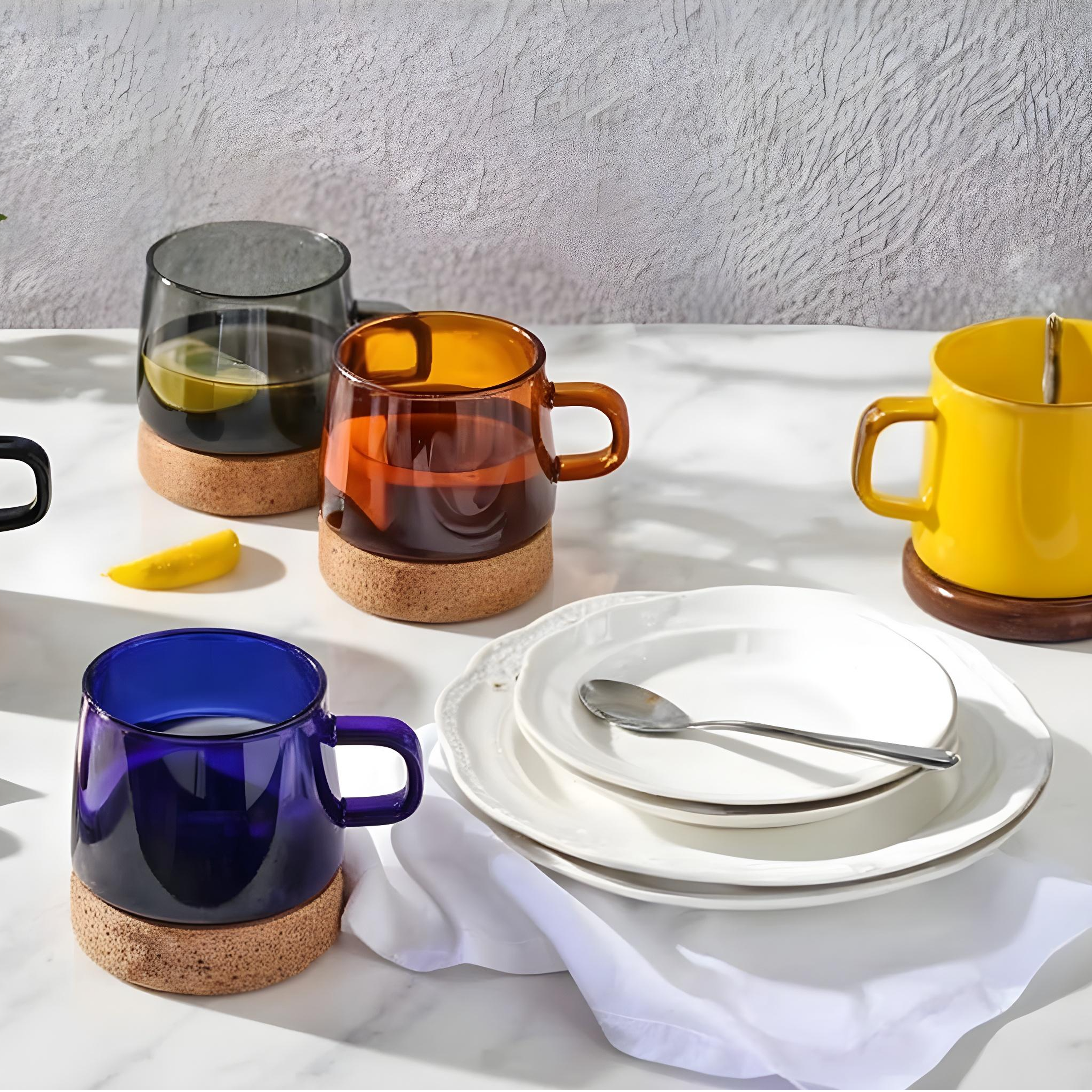 Colorful glass mugs and stacked white plates with spoon