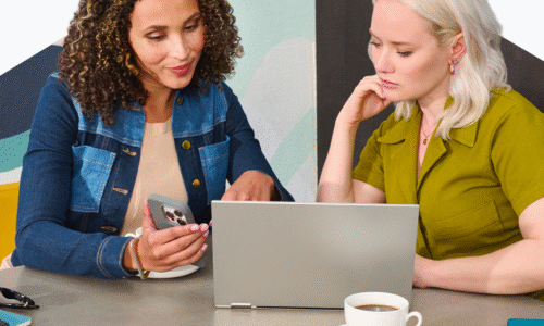 Two women collaborating with laptop and smartphone