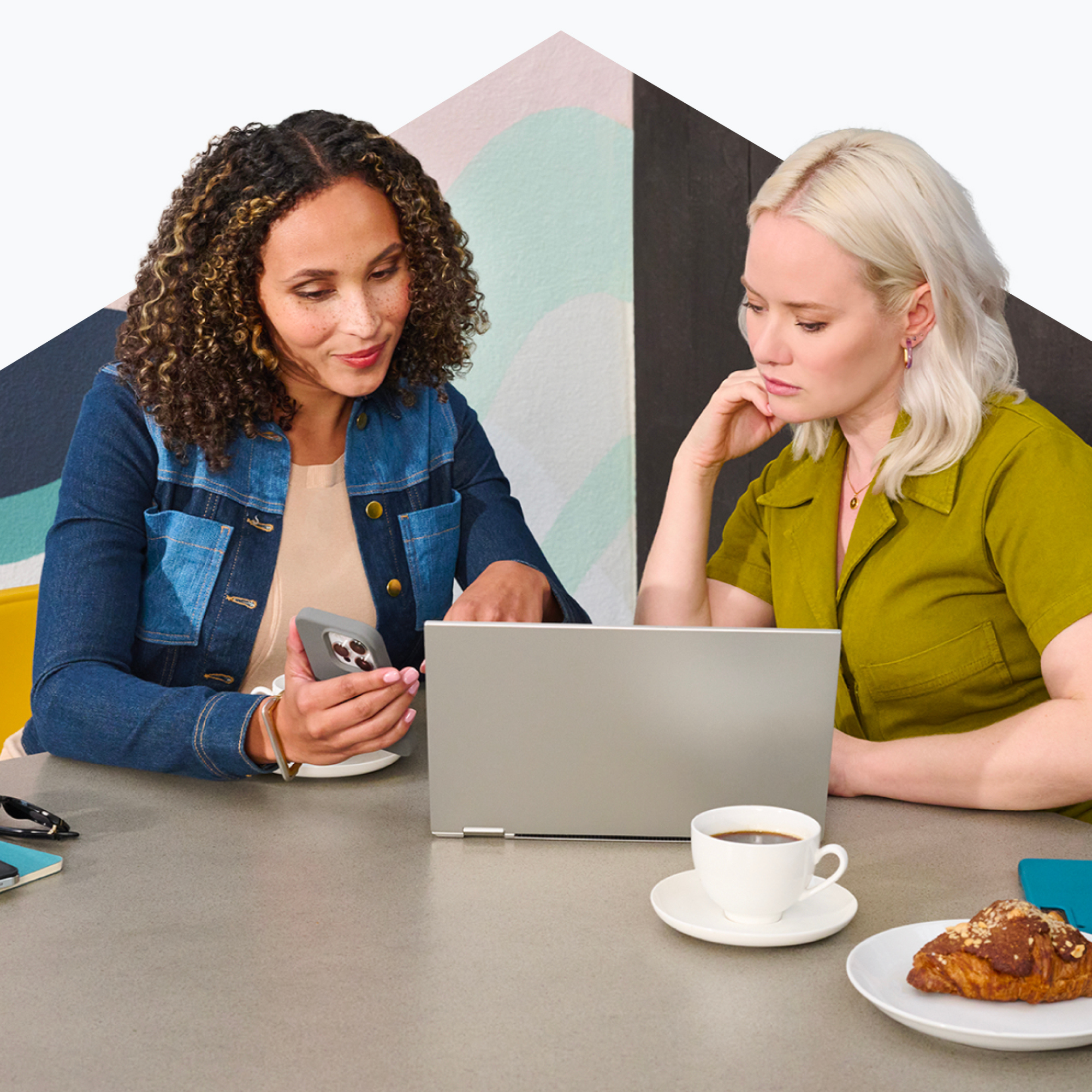 Two women collaborating with laptop and smartphone