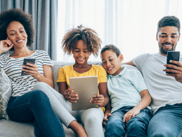 Family using tablets and smartphones together on couch