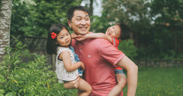 Father carrying smiling children outdoors in garden