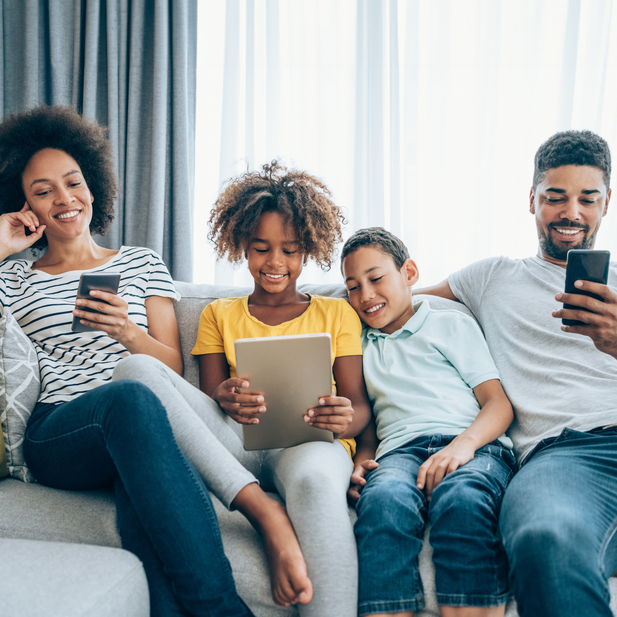 Family using smartphones and tablet on couch