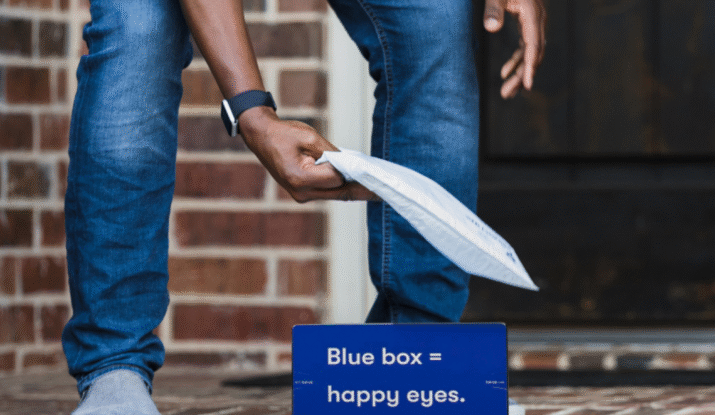 Person picking up packages from doorstep with blue box