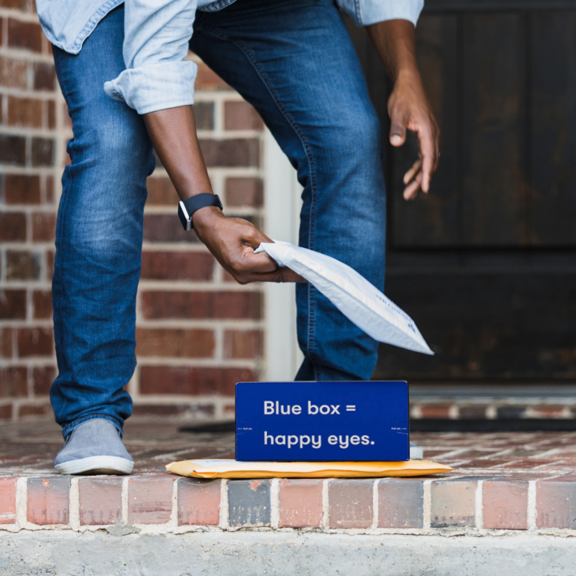 Person picking up packages from doorstep with blue box