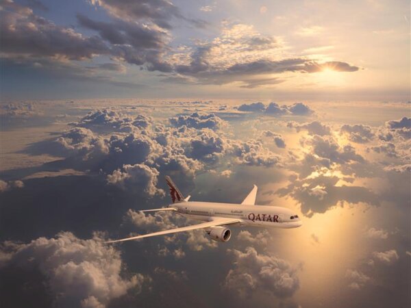 Qatar Airways plane flying above clouds at sunset