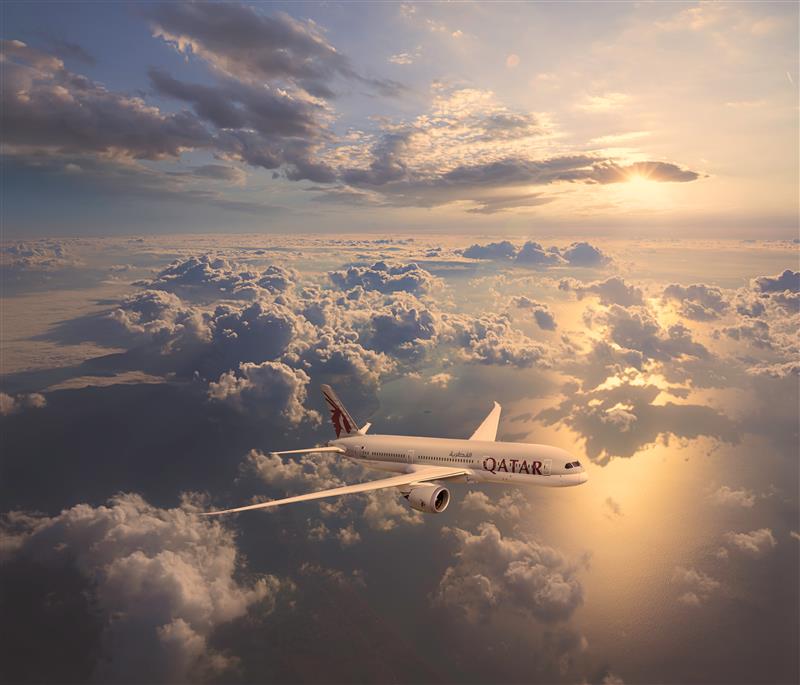 Qatar Airways plane flying above clouds at sunset