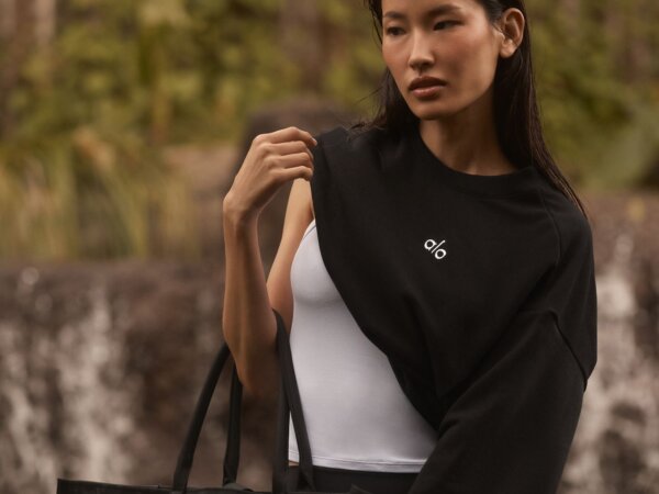 Woman wearing black alo sweatshirt carrying black tote bag