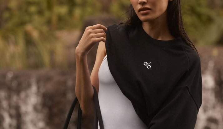 Woman wearing black alo sweatshirt carrying black tote bag