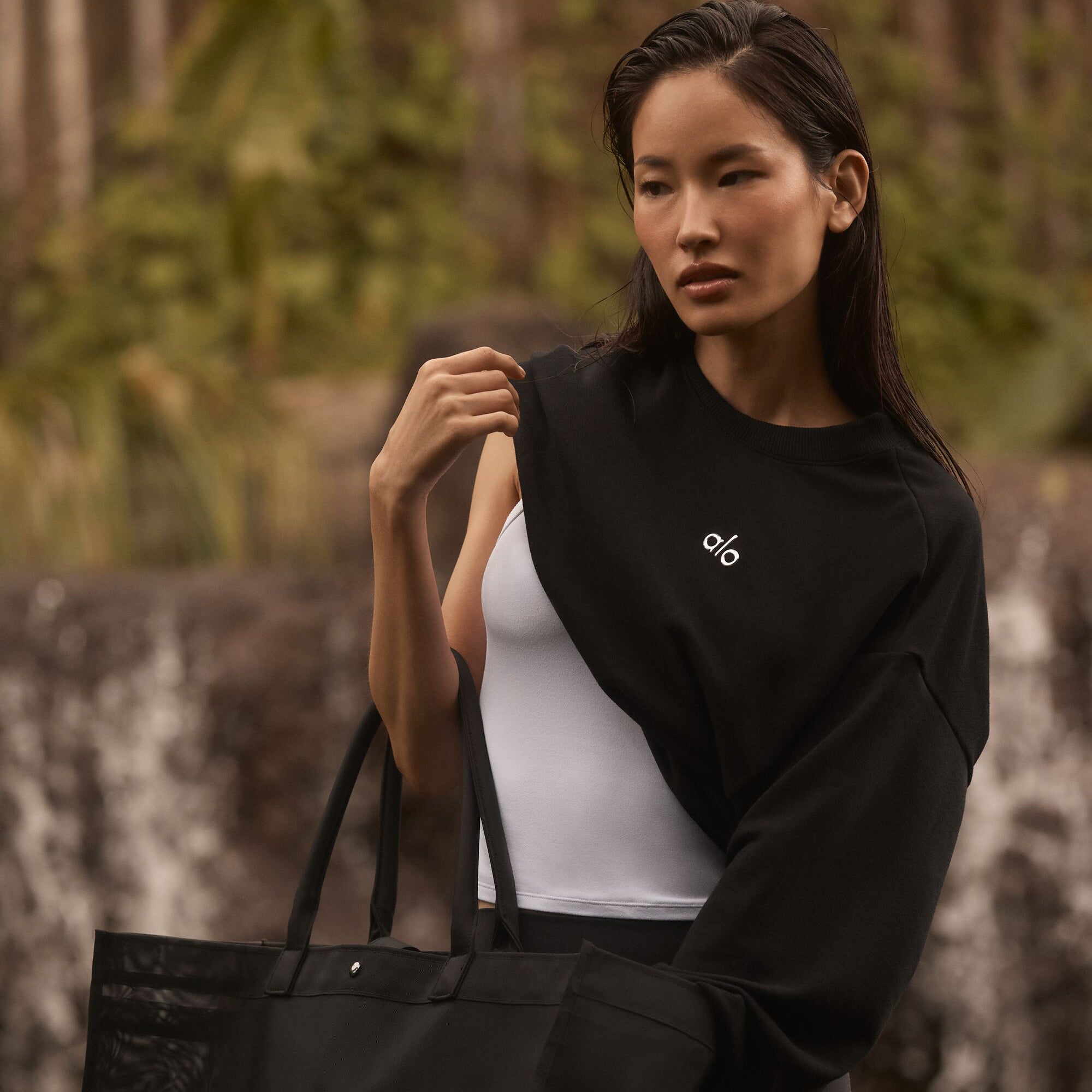 Woman wearing black alo sweatshirt carrying black tote bag