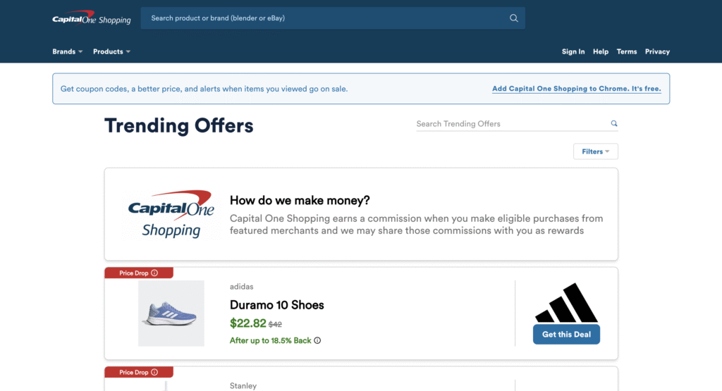 Online shopping page showing Capital One Shopping logo and explanation of commission, trending offers including Adidas Duramo 10 Shoes at $22.82 with a price drop, and a Stanley product offer, with a search bar and navigation links at the top.