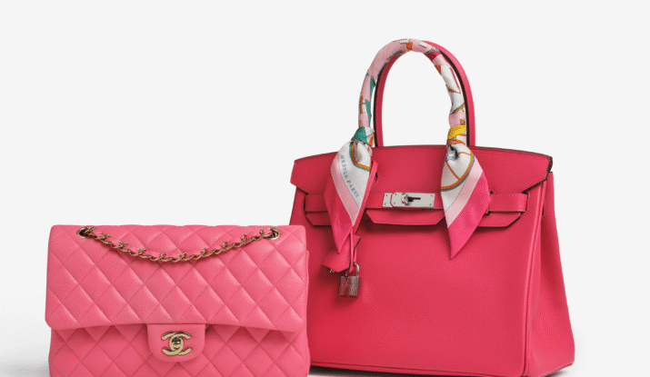 Two pink luxury handbags on a white surface, one quilted Chanel flap bag with a gold chain strap and the other a Hermès Birkin with a colorful silk scarf wrapped around the handle and a silver lock detail
