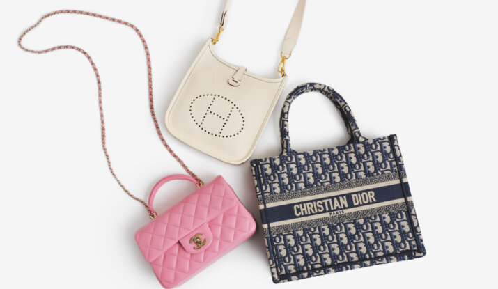 Three designer handbags on a white background: a white Hermes crossbody bag with perforated logo, a pink Chanel quilted leather handbag with chain strap, and a blue Christian Dior logo tote bag.