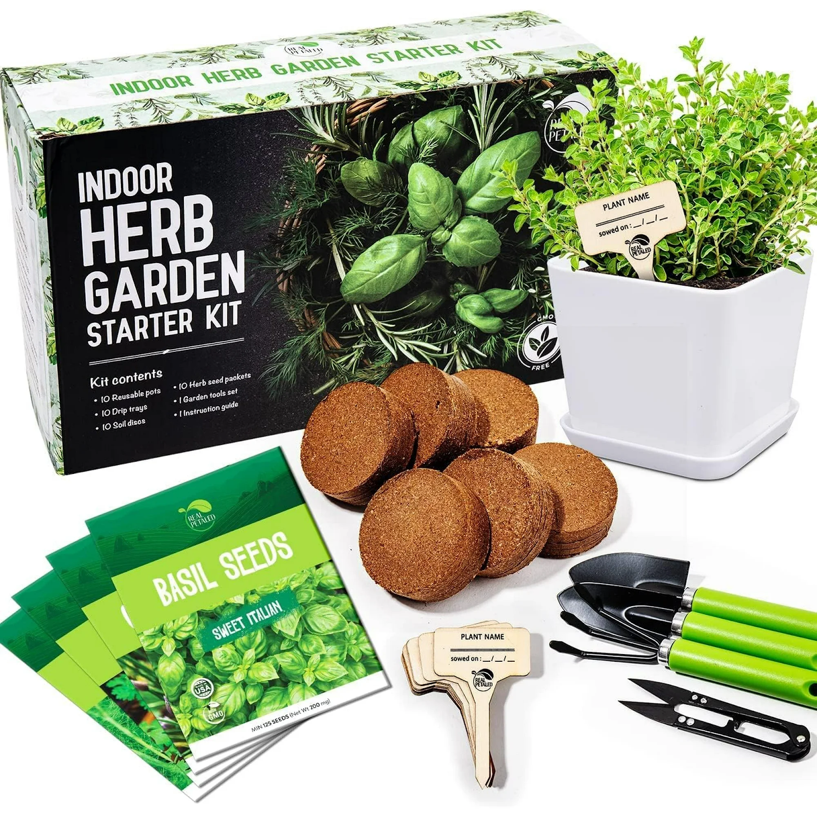 Indoor herb garden starter kit containing reusable pots, soil discs, herb seed packets, garden tools with green handles, plant name markers, and a small potted herb plant in a white square pot.