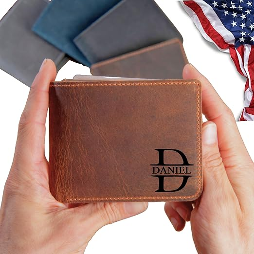 Hands holding a brown leather wallet personalized with the name Daniel in black text, with three additional wallets and a partially visible American flag in the background