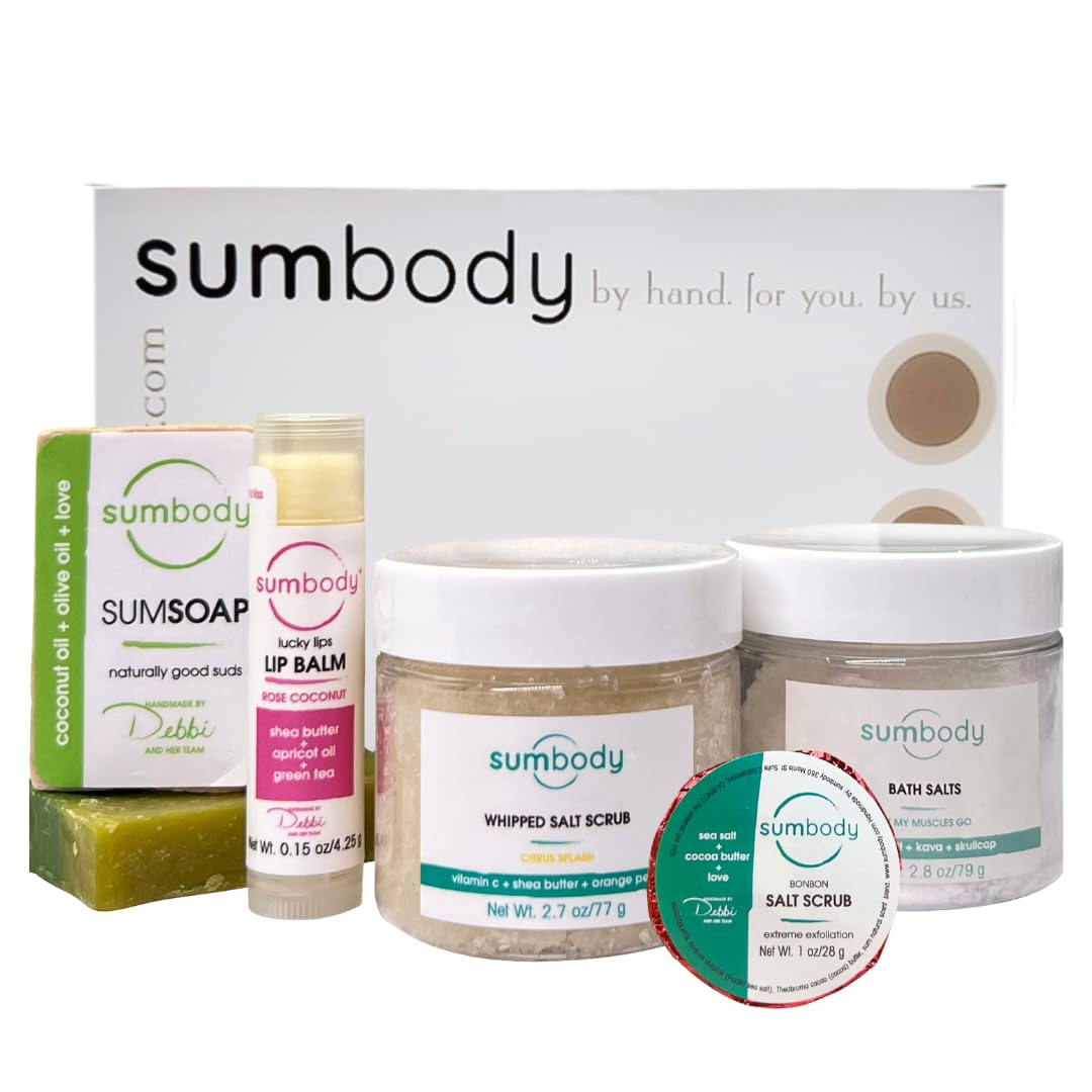 Assortment of Sumbody skincare products including a bar of soap, lip balm, two jars of salt scrubs, and a tub of bath salts placed in front of a white Sumbody branded box.
