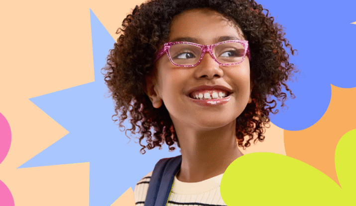 Young girl with curly hair wearing pink glasses and a striped shirt, smiling and looking to the side, against a colorful abstract background of star and flower shapes.