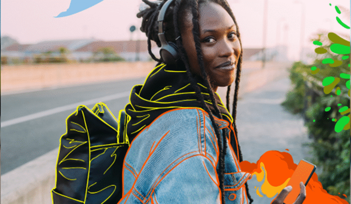 Young person with dreadlocks wearing headphones and a denim jacket outlined with bright colors, carrying a black backpack also outlined, holding a smartphone with fiery orange-red digital effects, standing on a sidewalk next to a road at sunset.