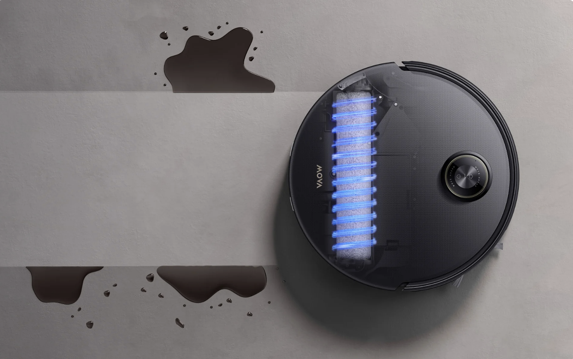 Top view of a black robotic vacuum cleaner cleaning a dark liquid spill on a light grey floor, with a highlighted blue cylindrical brush visible through a transparent section on the vacuum's top surface.
