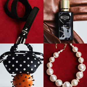 Composite image of four items: top left shows a black cat-shaped zipper pull on a black strap against a red background; top right shows a black bottle of "Blue Talisman" perfume resting on brown leather; bottom left shows a black polka-dotted gathered purse atop an orange covered in cloves; bottom right shows a gold chain necklace decorated with large white pearls on a red background.