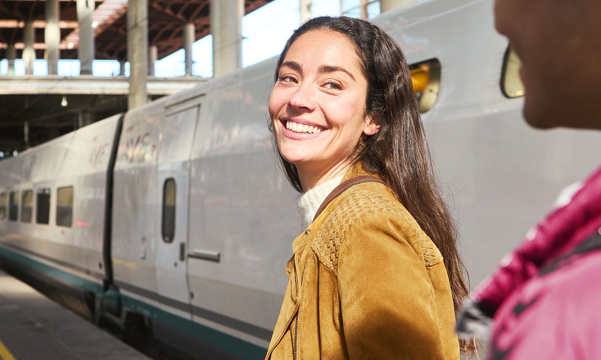 Smiling woman with suitcase at train station platform