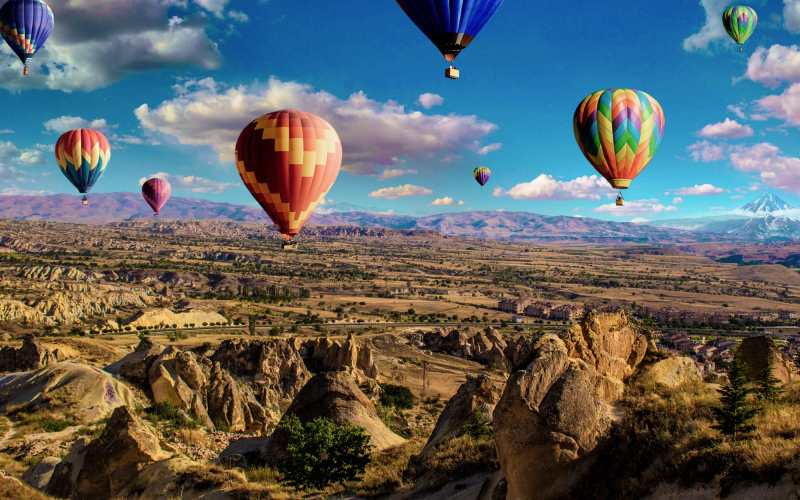 Colorful hot air balloons floating over rocky landscape