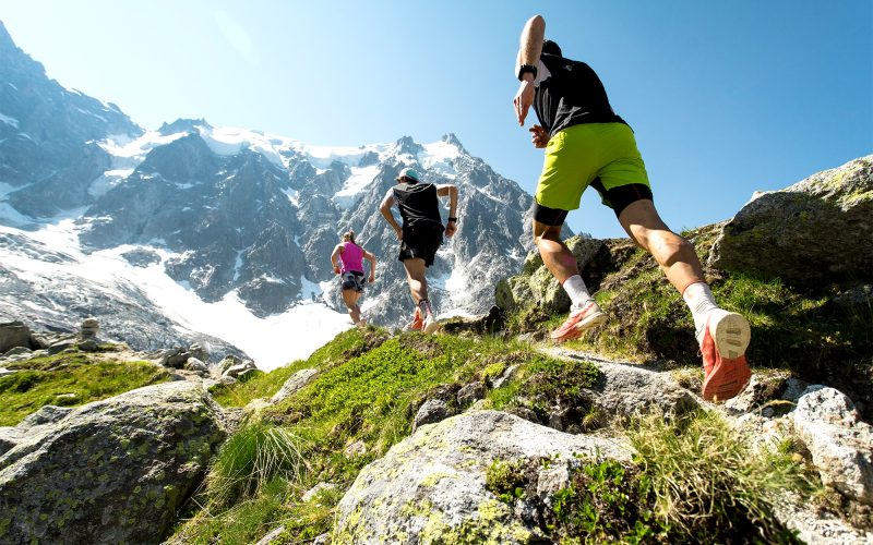 Three runners climbing rocky mountain trail