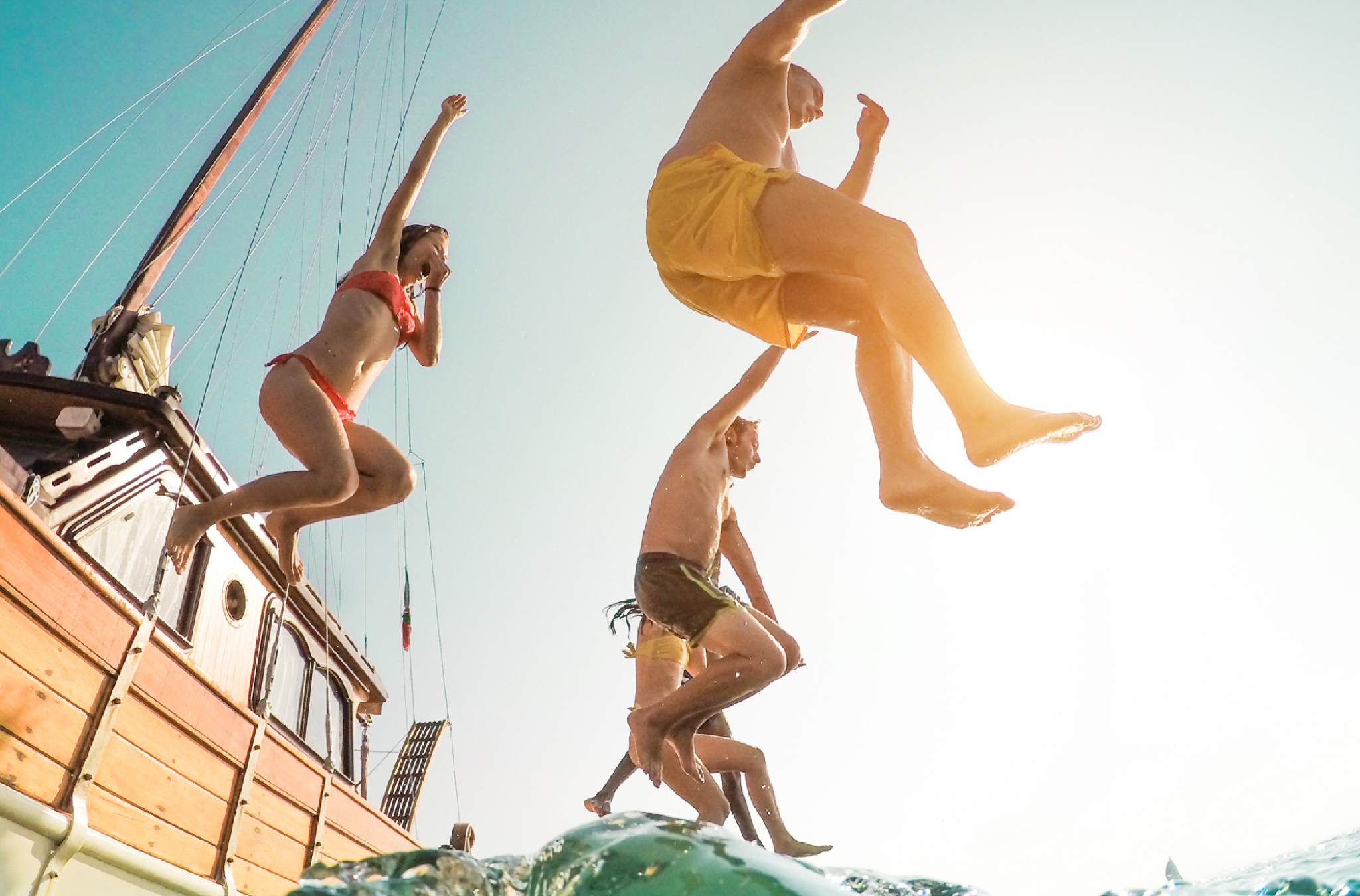 People jumping off wooden boat into sea